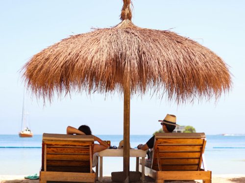 Sombrilla de palma y tumbonas en la playa de Bela Beach